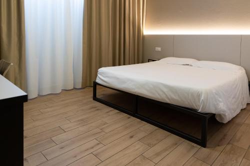 a bedroom with a white bed and a wooden floor at Hotel Astoria in Ravenna