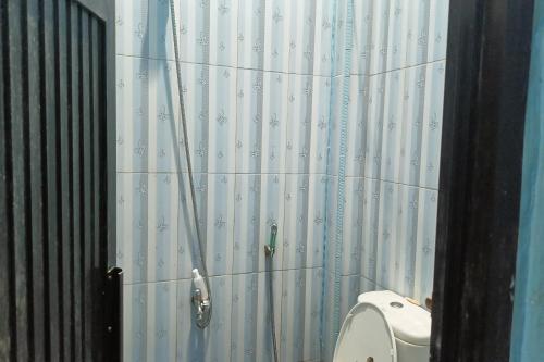 a bathroom with a toilet and a shower curtain at OYO 93875 Tifar House in Pallenguk