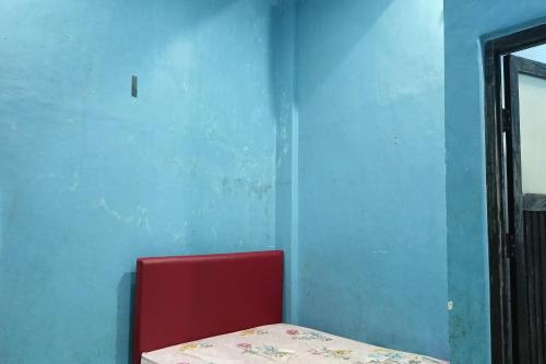 a red chair in a room with a blue wall at OYO 93875 Tifar House in Pallenguk