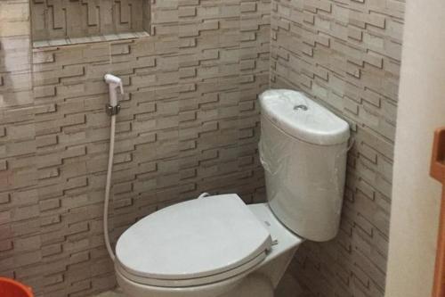 a bathroom with a white toilet with a hose at OYO 93866 Neva Guest House Syariah in Parit