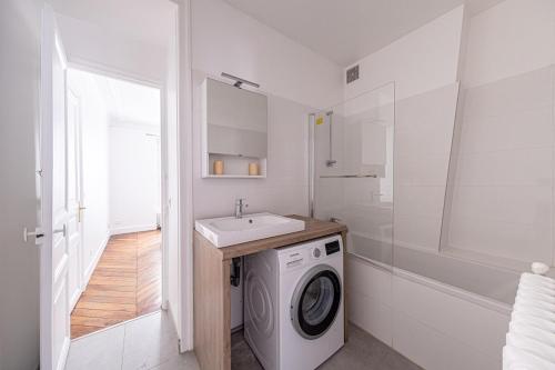 uma casa de banho branca com uma máquina de lavar roupa e um lavatório em Appart Triomphe Champs Elysées em Paris