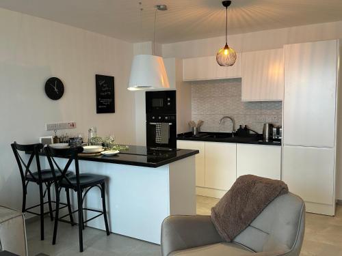a kitchen with a counter and a bar with chairs at Penthouse i sjøkanten på Dejablue in Kérynia