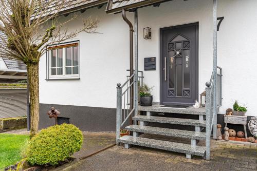 a white house with a gray door and stairs at Ferienwohnung Schätzle in Schuttertal