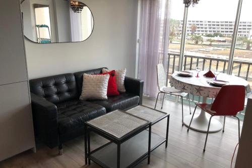 un salon avec un canapé noir et une table dans l'établissement Naturiste Cap d'Agde Héliopolis F 31, au Cap d'Agde