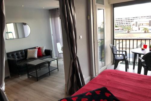 um quarto com um sofá e uma sala de estar com uma varanda em Cap d' Agde Naturiste Héliopolis F31 em Cap d'Agde