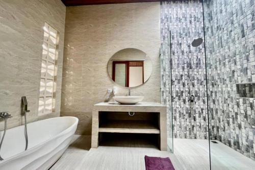 W łazience znajduje się wanna, umywalka i lustro. w obiekcie Belvilla 93823 Villa Gan Near Titi Batu Club Ubud w mieście Ubud
