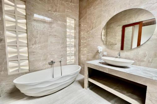 a bathroom with a large white tub and a sink at Belvilla 93824 Villa Nesa Near Titi Batu Club Ubud in Ubud