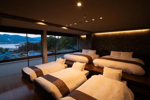 a room with four beds and a large window at Kikunoya in Miyajima