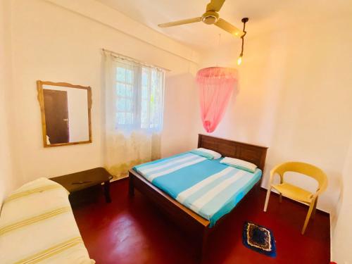 1 dormitorio con cama, espejo y silla en Hamba Hostel for Safari en Hambantota