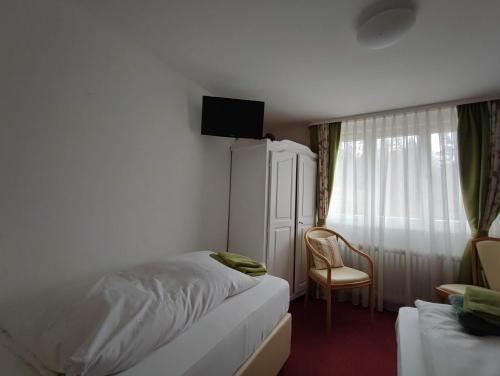 a bedroom with a bed and a chair and a television at Room in Guest room - Pension Forelle - double room 01 in Forbach