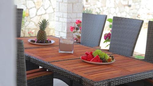 a wooden table with two plates of fruit and a drink at Luxury Villa Levanda in Ksamil