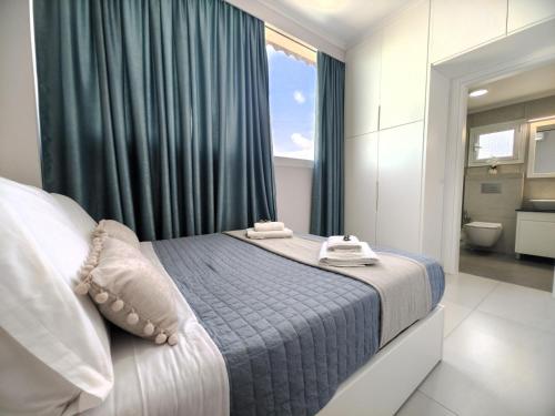 a bedroom with a bed with blue curtains and a bathroom at Luxury Villa Levanda in Ksamil