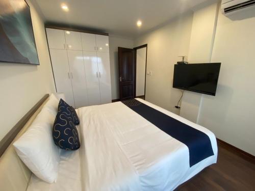 Schlafzimmer mit einem weißen Bett und einem Flachbild-TV in der Unterkunft SweetHome Long Biên in Hanoi
