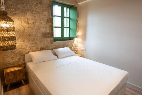 a white bed in a room with a window at Olvio Suites in Kardamili