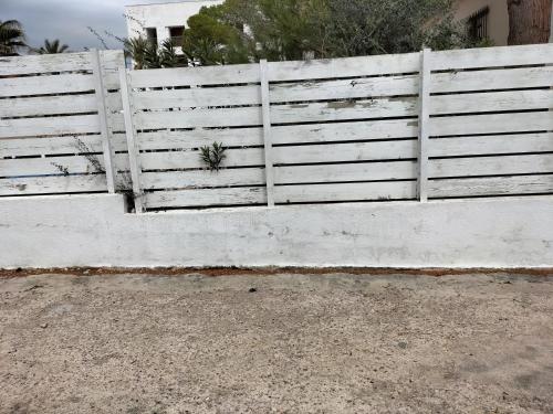 una cerca blanca frente a una casa en CASA MARINERA ALCOSSEBRE en Alcocéber