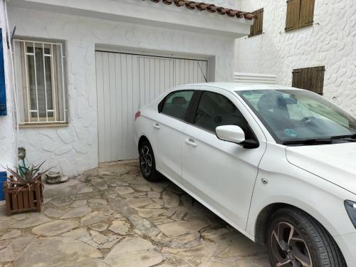 un coche blanco estacionado frente a un garaje en CASA MARINERA ALCOSSEBRE en Alcocéber
