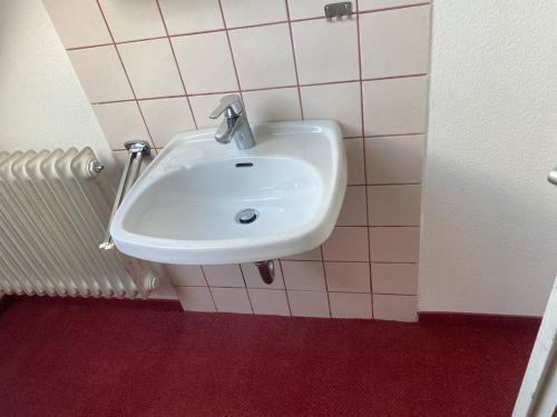 lavabo blanco en el baño con azulejos rosas en Room in Guest room - Single room with shared bathroom and kitchen in Forbach en Forbach
