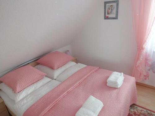 een slaapkamer met een roze en wit bed met 2 kussens bij Appartement in Burg Auf Fehmarn mit Terrasse, Garten und Grill in Fehmarn