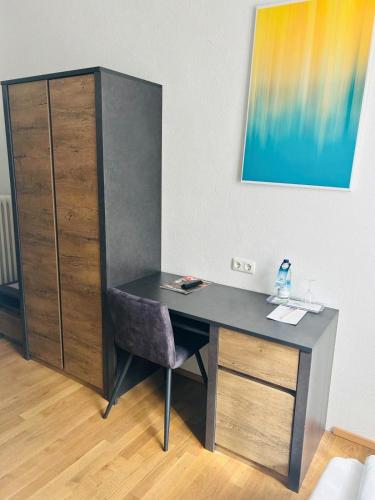 a desk with a chair next to a cabinet at Hotel Wendelstein in Rosenheim