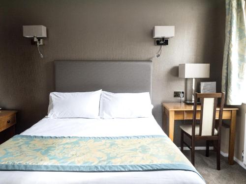 a bedroom with a bed and a desk with a chair at Victoria Park Lodge in Leamington Spa