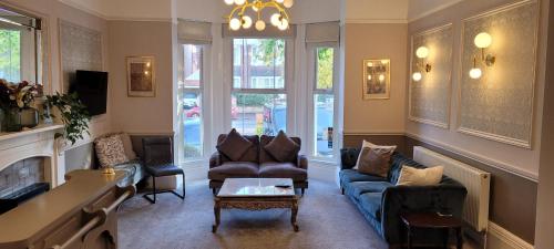 un soggiorno con divano blu e sedie di Victoria Park Lodge & Serviced Apartments a Leamington Spa