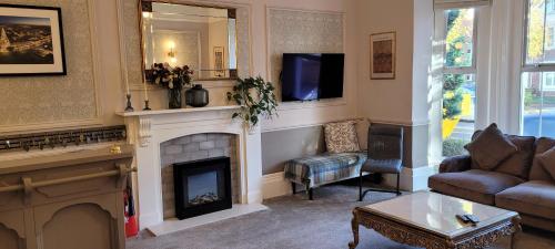 a living room with a fireplace and a tv at Victoria Park Lodge & Serviced Apartments in Leamington Spa