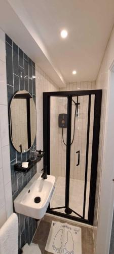 a bathroom with a sink and a shower with a mirror at Victoria Park Lodge in Leamington Spa