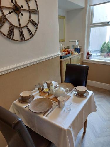 einen Tisch mit Tellern und eine große Uhr an der Wand in der Unterkunft Storrbeck Guest House in Whitby