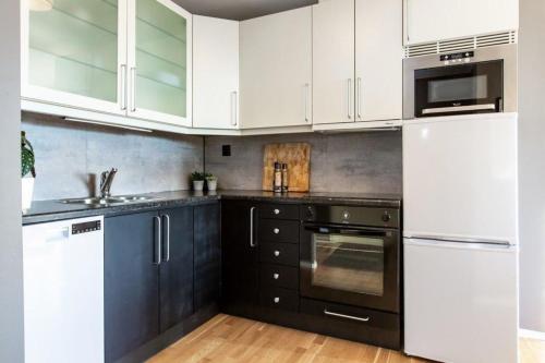 una cocina con armarios blancos y electrodomésticos negros en Ferienwohnung für 2 Personen ca 35 qm in Haugesund, Südnorwegen en Haugesund