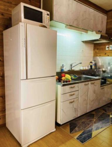 a kitchen with a white refrigerator and a sink at 箱根 邂逅 ログハウス 森林浴とBbqが楽しめる in Ashinoyu