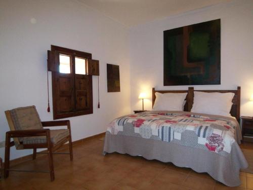 Un dormitorio con una cama y una silla y una ventana. en Dachterrassen-Loft mit Bergblick, en Sencelles