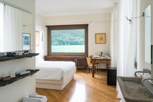 1 dormitorio con cama, ventana y escritorio en Villa Noseda, en Moltrasio