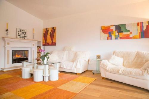 uma sala de estar com dois sofás brancos e uma lareira em Ferienhaus in Seefeld In Tirol mit Großer Terrasse em Seefeld no Tirol