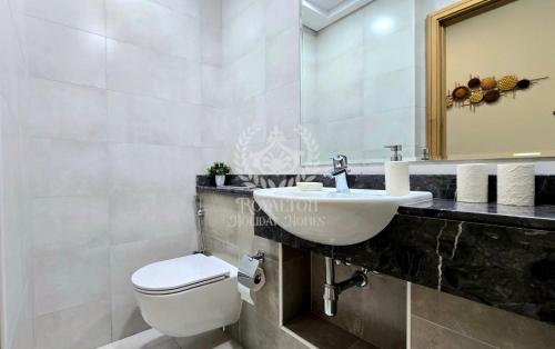 ein Badezimmer mit einem Waschbecken, einem WC und einem Spiegel in der Unterkunft Royalton - Vibrant Cityscape 1BR Next to Business Bay Canal in Dubai