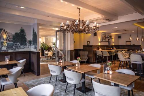un restaurante con mesas de madera y sillas blancas en Hotel Aalsmeer, en Aalsmeer