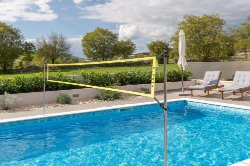 einen Pool mit einem Volleyballnetz und zwei Stühlen in der Unterkunft Ferienhaus für 6 Personen ca 150 qm in Sičane, Dalmatien Dalmatinisches Hinterland in Sičane