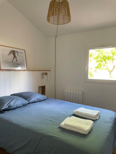 um quarto com uma cama com duas toalhas em La Pinède - Séjour idéal entre plage et lac em Lacanau