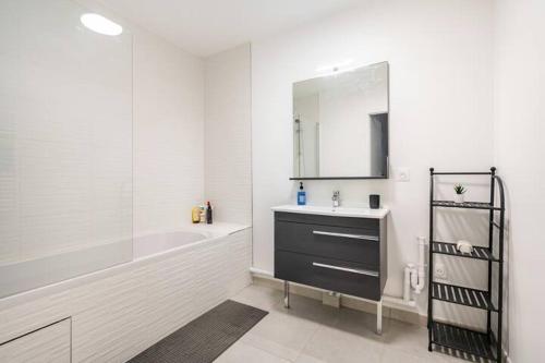 une salle de bain avec un lavabo, une baignoire et un miroir dans l'établissement Home-like apartment Near DisneyLand, à Chessy