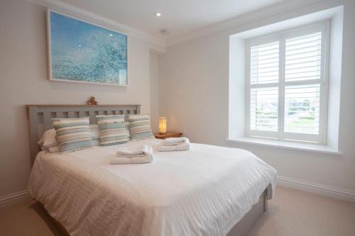 a white bedroom with a bed with towels on it at Chy An Gweal Farm Cottage in Carbis Bay