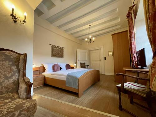 a bedroom with a bed and a chair in a room at Hotel Schloss Zell in Zell an der Mosel