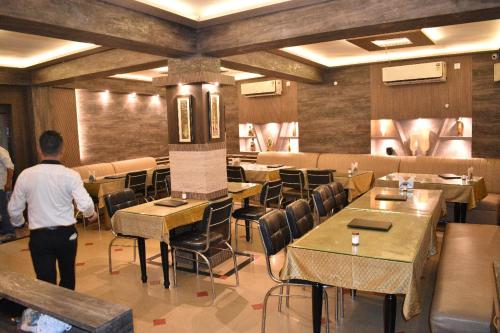 a man standing in a restaurant with tables and chairs at MAYUR HOTEL in Dimāpur