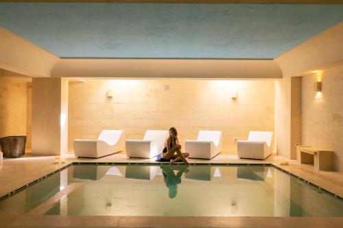 a woman sitting on the floor next to a pool at Alvino Relais Mulino Contemporaneo in Matera