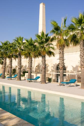 a pool with palm trees in front of a building at Alvino Relais Mulino Contemporaneo in Matera