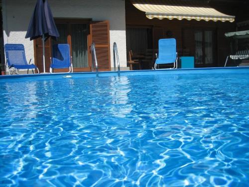 una grande piscina con sedie blu e ombrellone di Geräumige Wohnung in Gemeinde Flattach mit Großer Terrasse a Flattach
