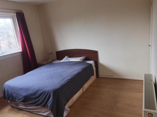 a bedroom with a bed with a blue comforter and a window at Glasgow Double Room Free Parking in Glasgow