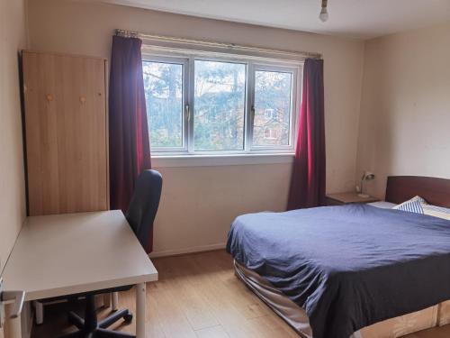 a bedroom with a bed and a desk and a window at Glasgow Double Room Free Parking in Glasgow
