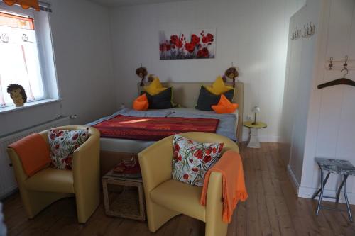 um pequeno quarto com uma cama e 2 cadeiras em Ferienwohnung Maurer em Mücheln