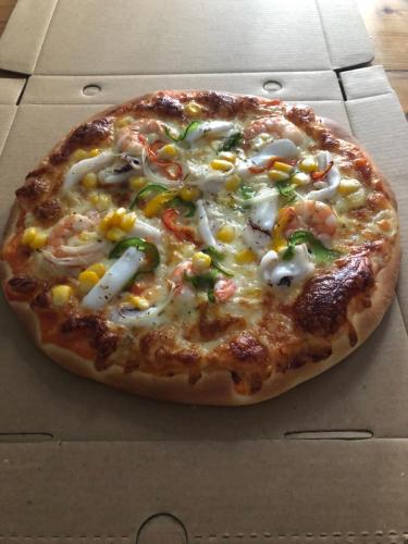 a pizza with cheese and vegetables in a box at Sunrise Dốc Lết in Ninh Hai