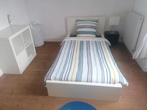 1 cama blanca con colchón a rayas en una habitación en Maison entre ville et campagne, en Amilly