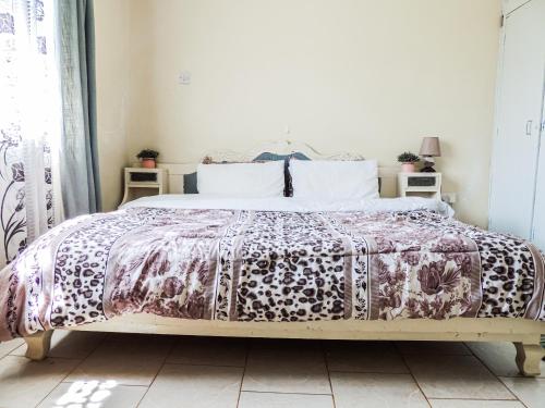 a bedroom with a bed with a purple bedspread at 3BR Serene Bungalow in Lower Kabete in Nairobi